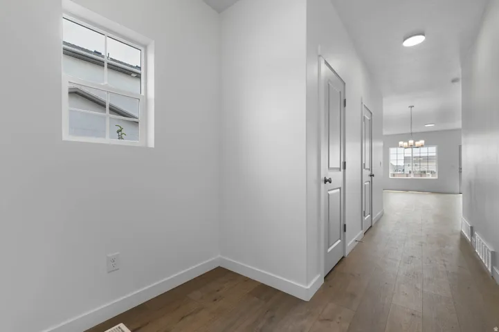 Hallway featuring wood-finish flooring, crisp white walls, and recessed lighting