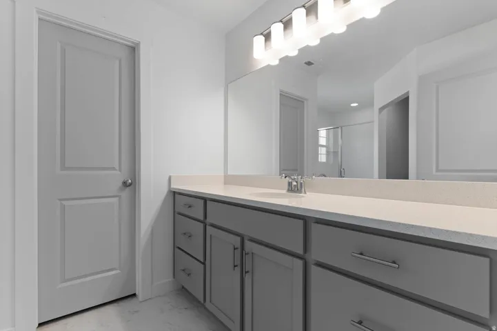 Spacious vanity with a light-toned countertop, dual sinks, and contemporary gray cabinetry featuring satin nickel hardware