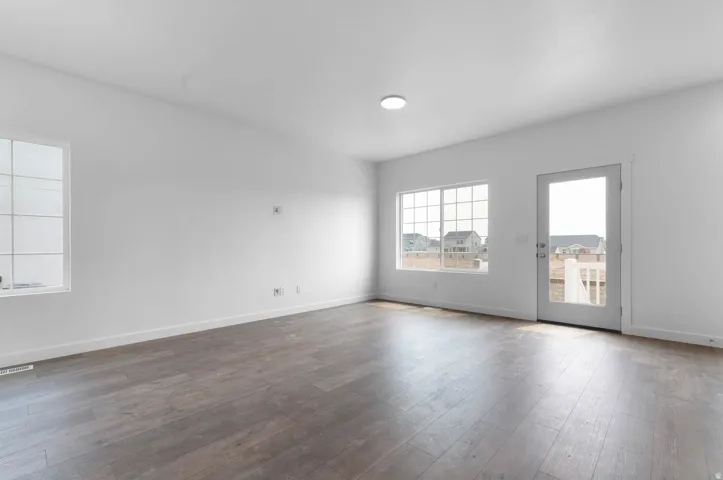 Spacious room featuring wood-finish flooring, white baseboards, and a neutral wall palette