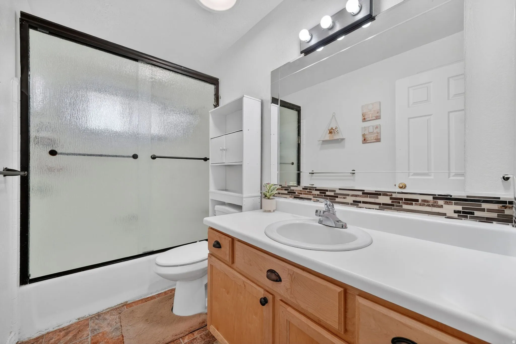 Full bathroom with vanity, shower / bath combination with glass door, and decorative backsplash