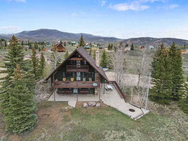 Rear view of property with a mountain view, a chimney, and a balcony