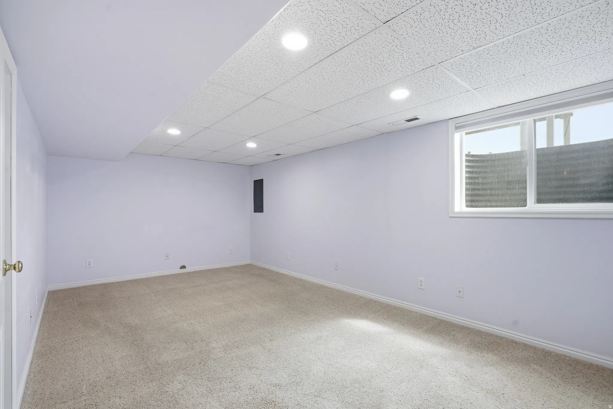 Carpeted empty room featuring a drop ceiling and recessed lighting