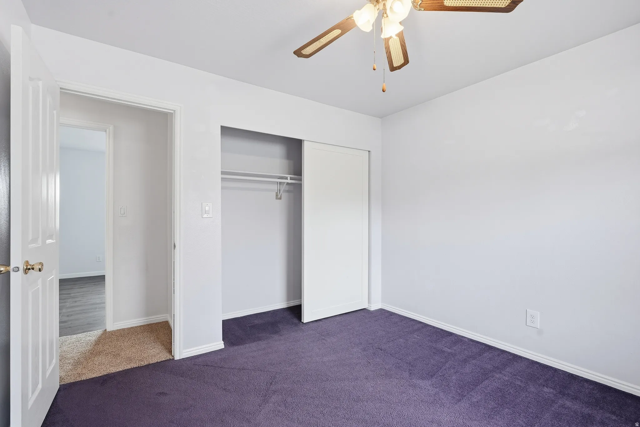 Unfurnished bedroom featuring dark colored carpet, a closet, and ceiling fan