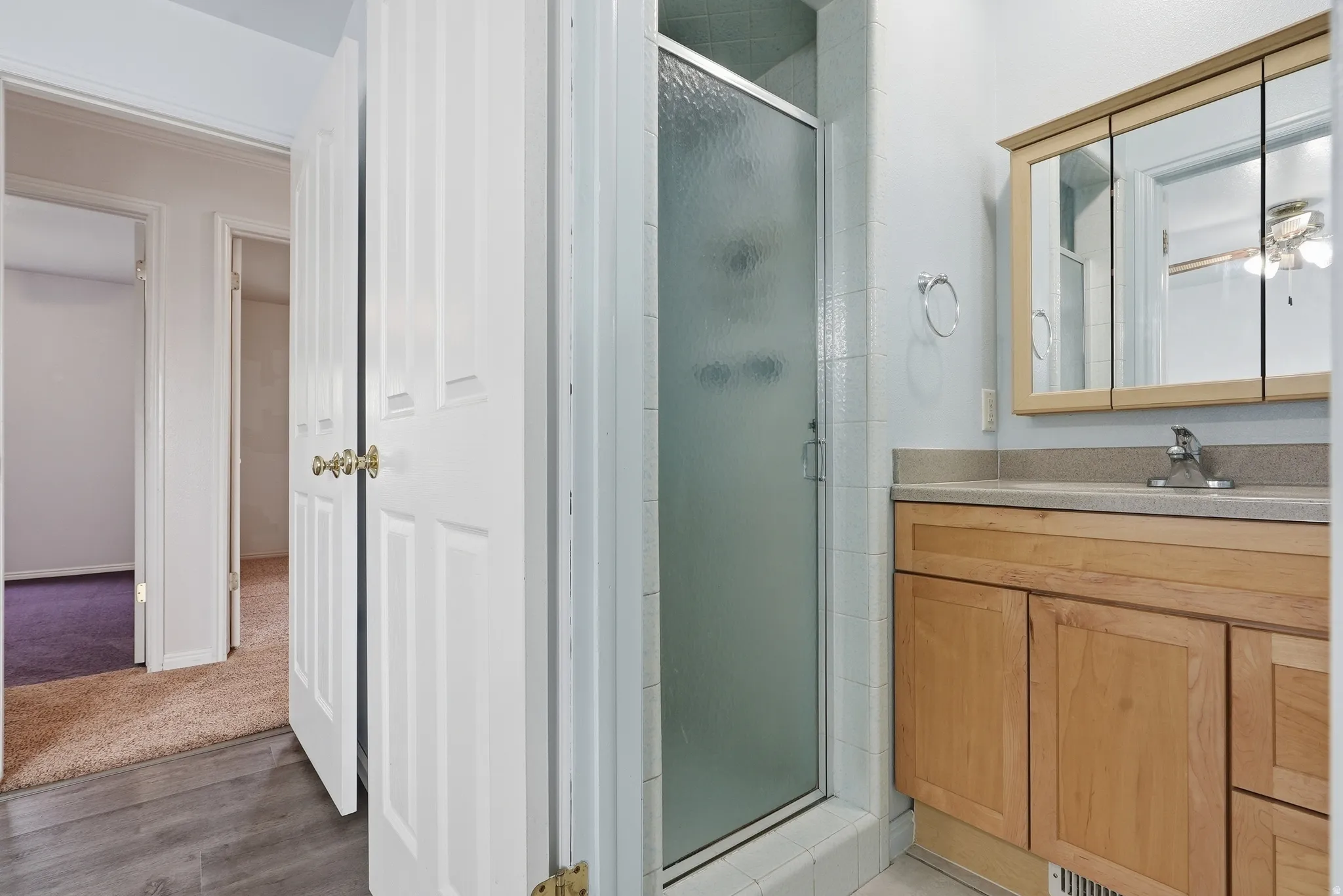 Bathroom with vanity, a shower stall, light wood finished floors, and ceiling fan