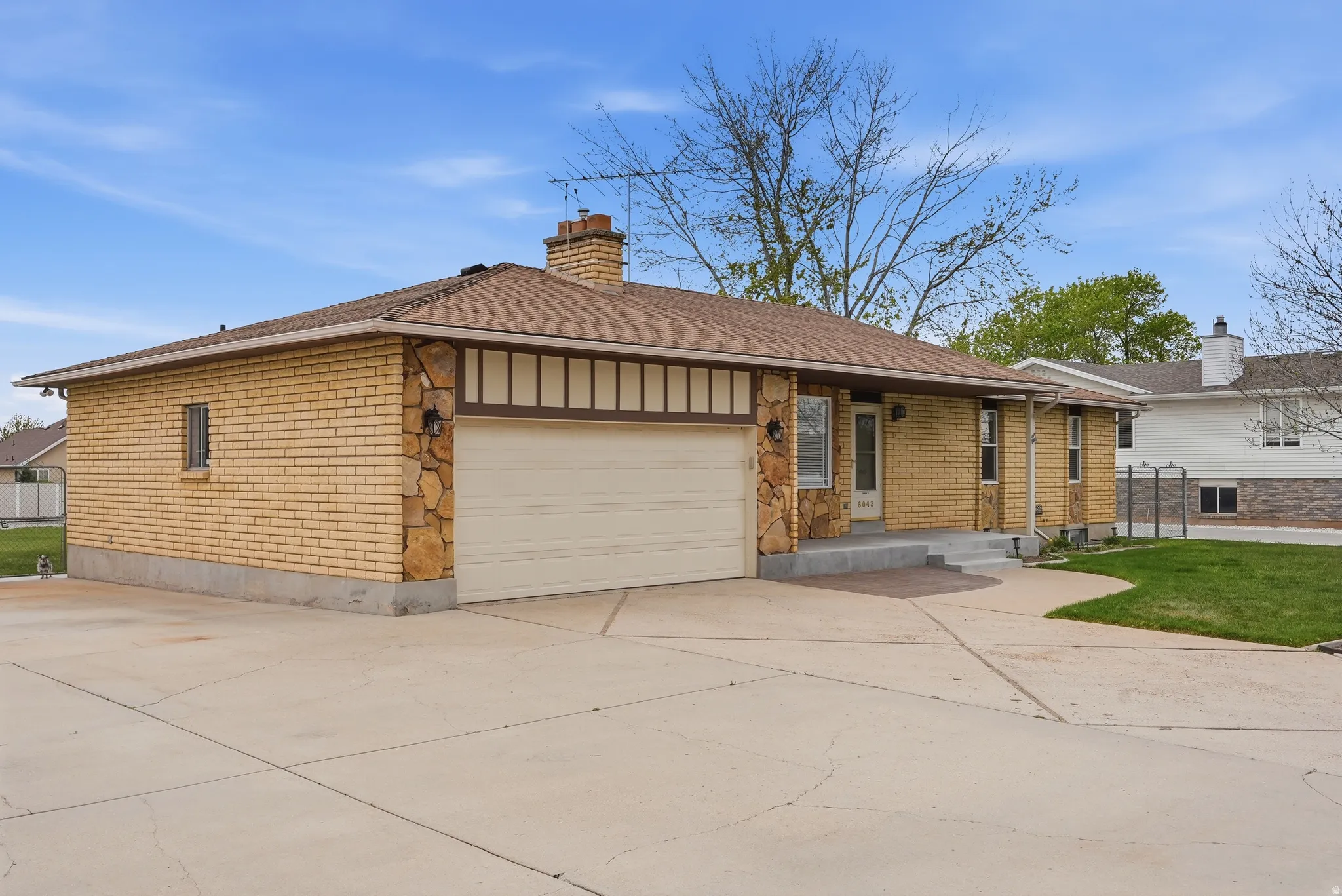 View of front of house featuring a garage, driveway, a chimney, brick siding, and roof with shingles