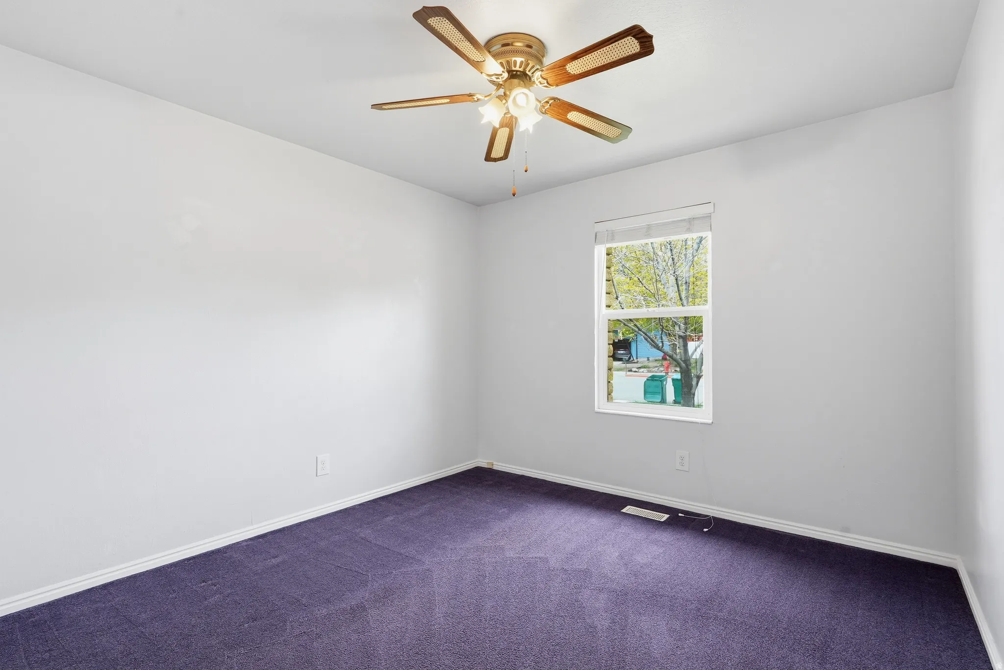 Unfurnished room featuring dark colored carpet and ceiling fan