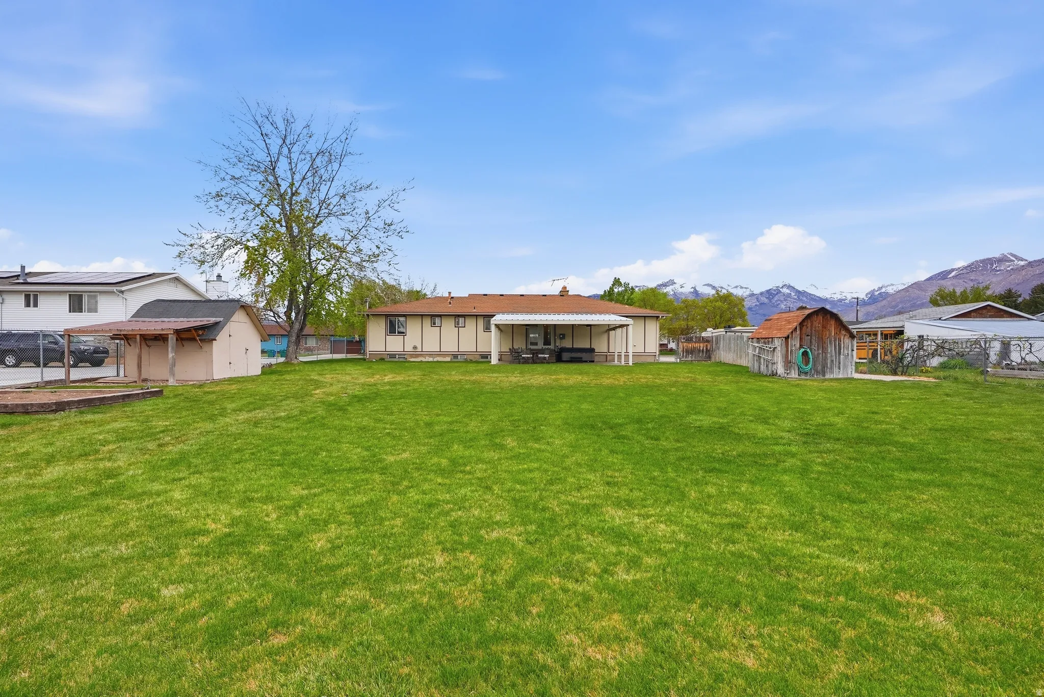 Rear view of property featuring a mountain view, a patio area, a storage unit, and board and batten siding