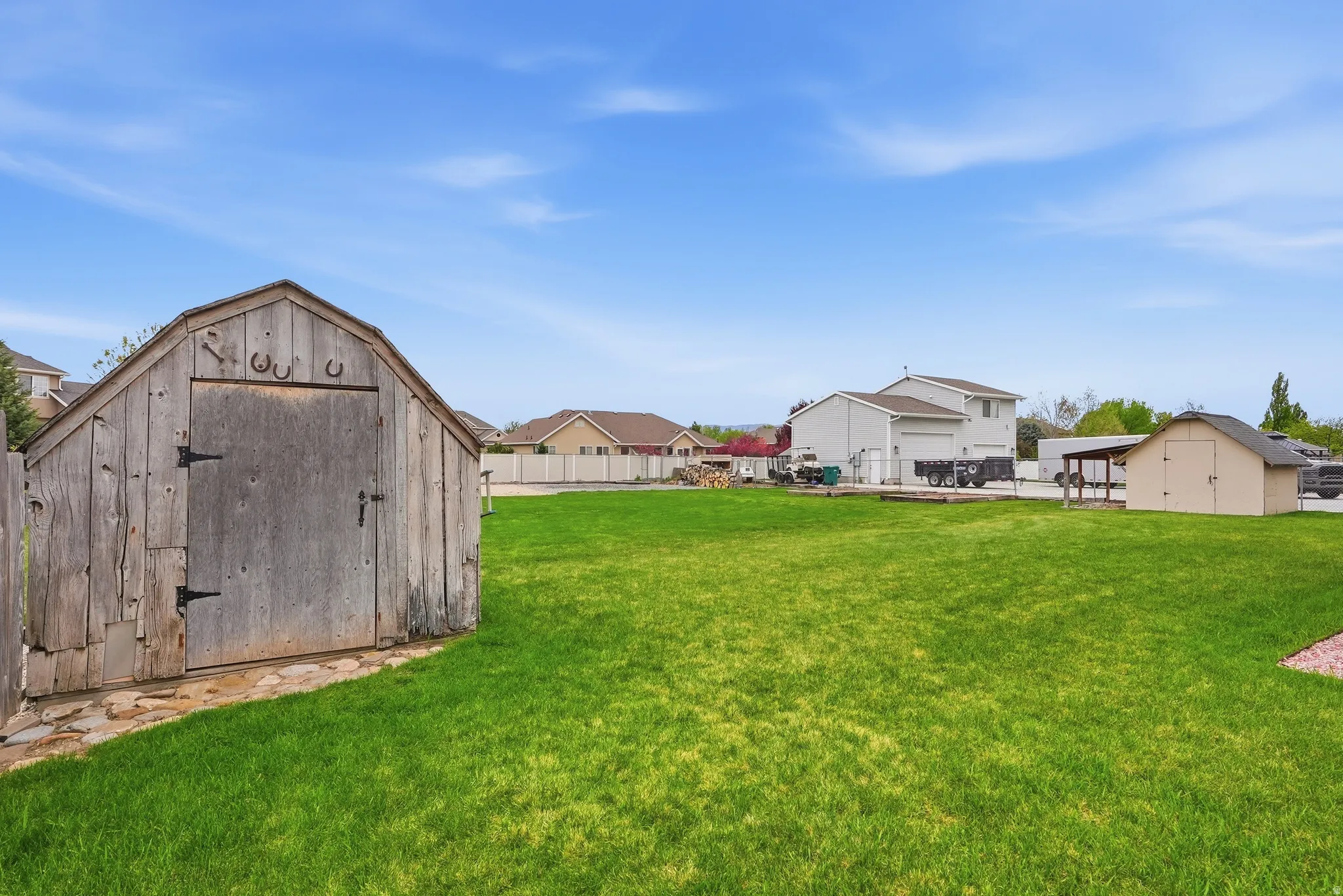 Fenced backyard featuring a storage unit and a residential view