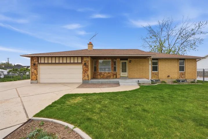 Ranch-style home with a porch, driveway, an attached garage, a chimney, and brick siding