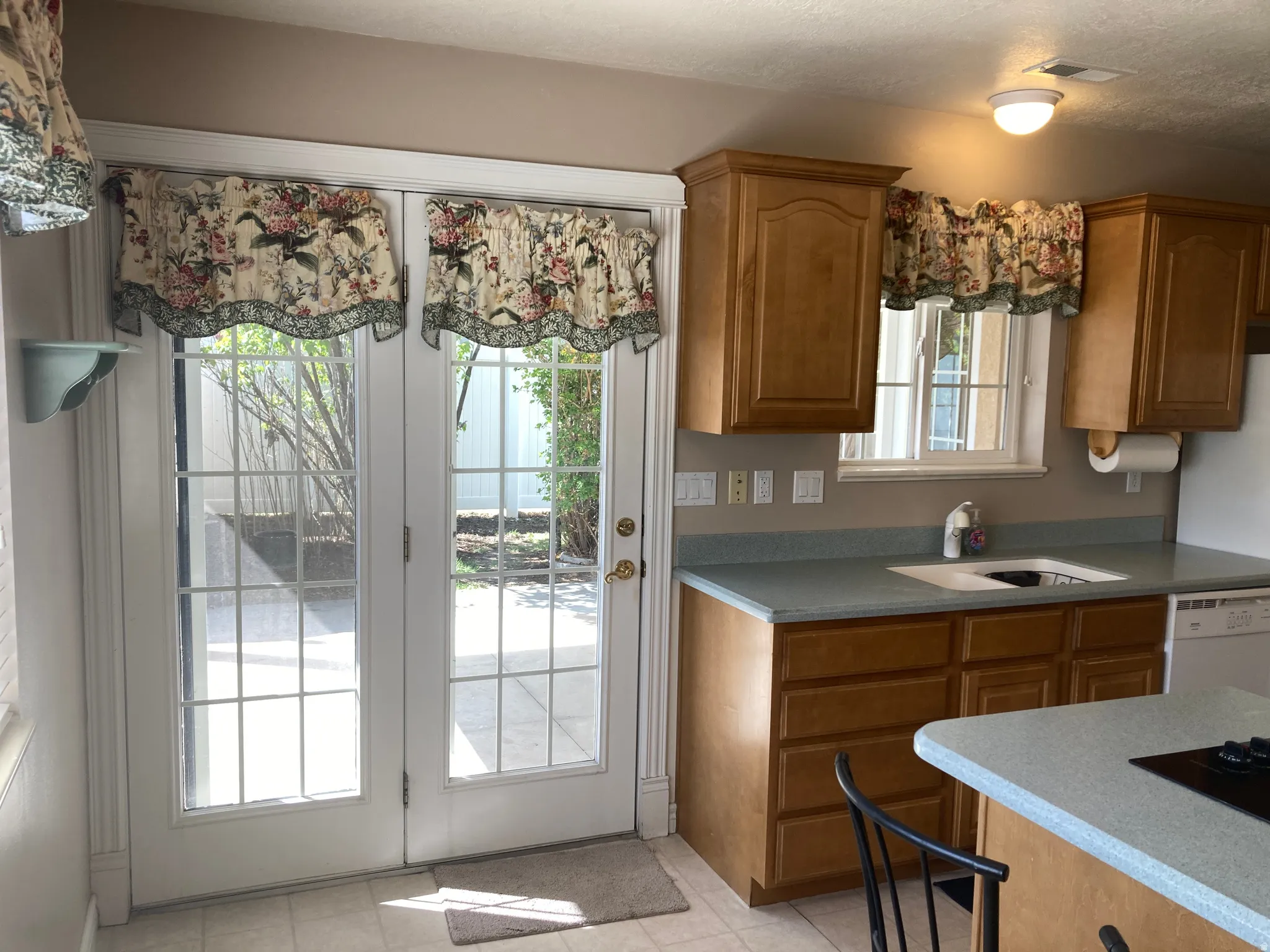 Kitchen featuring wood finish cabinets, dishwasher, and light tile patterned floors