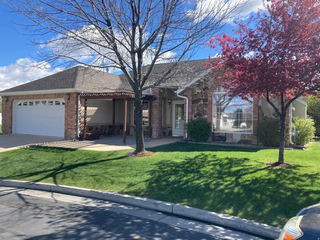 Ranch-style house with brick siding, an attached garage, a front yard, and a shingled roof