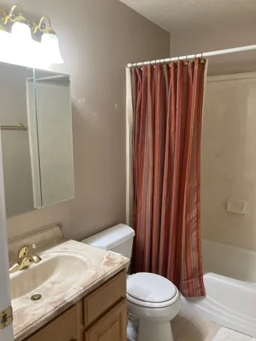 Bathroom with vanity, shower / bath combo with shower curtain, and tile patterned floors