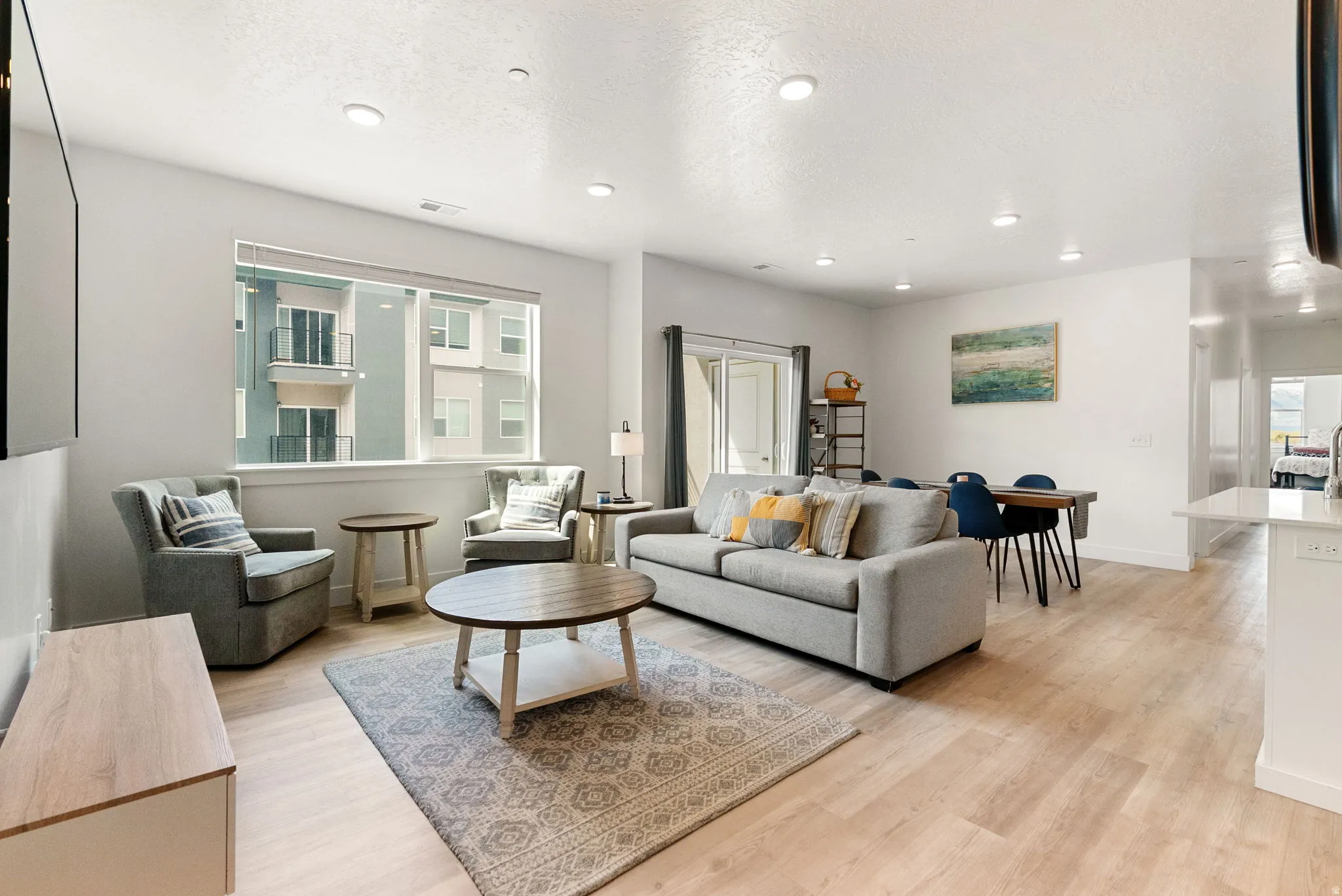 Living area with light wood-type flooring, recessed lighting, and a textured ceiling