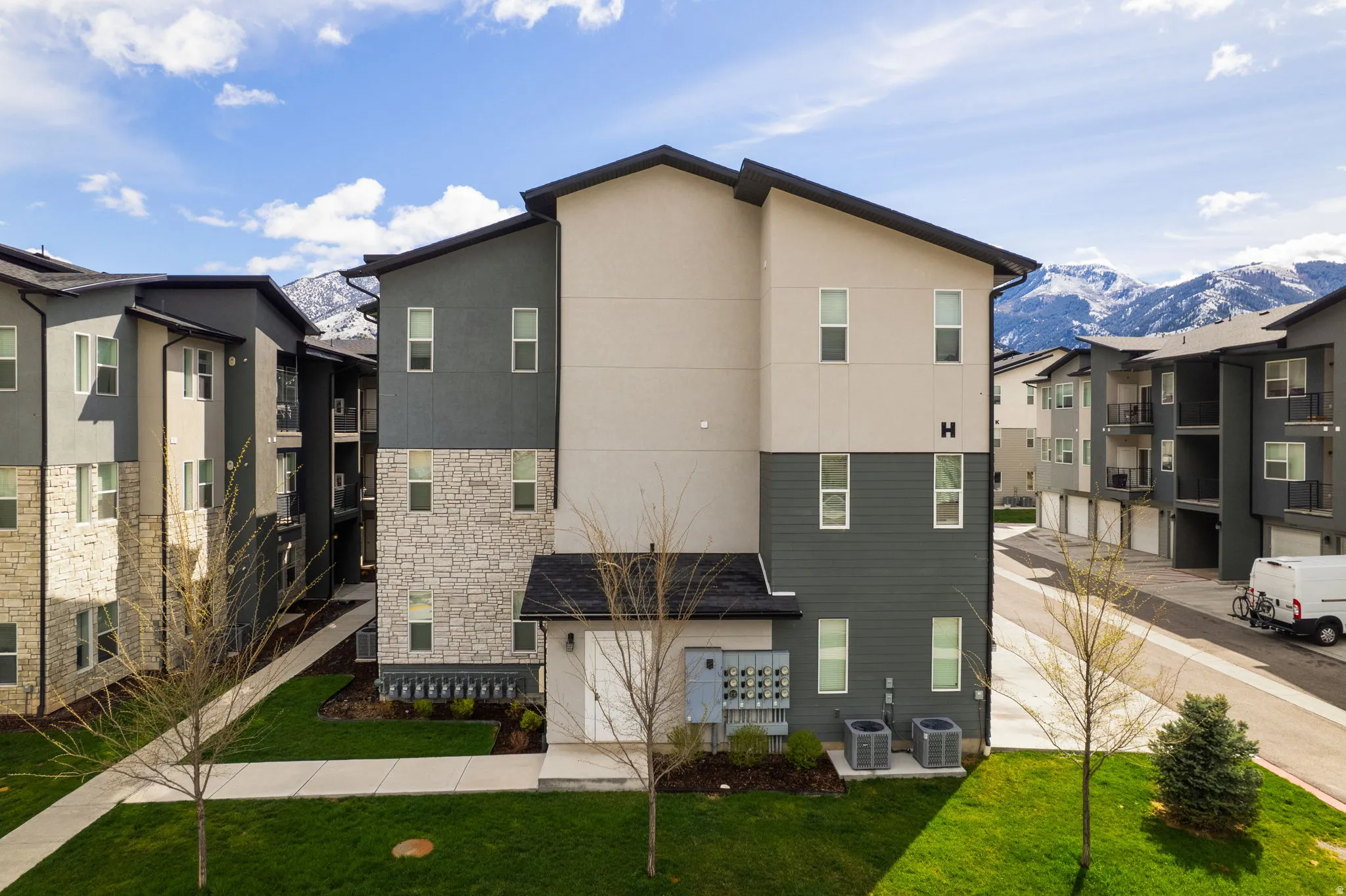 Back of house featuring stucco siding, stone siding, a mountain view, and a lawn