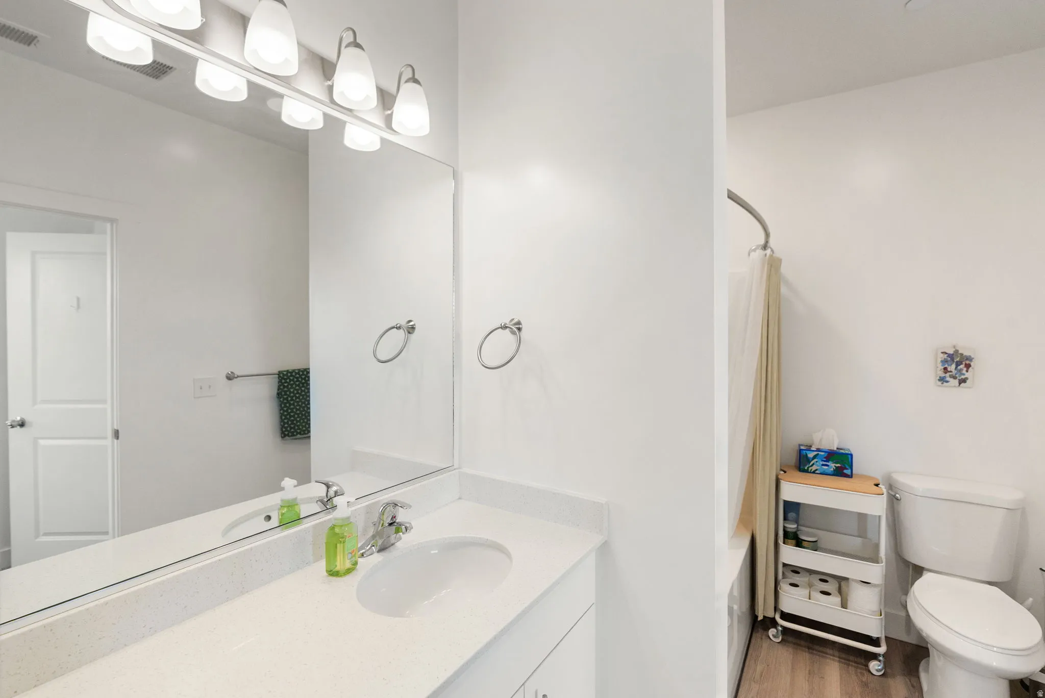 Bathroom with vanity, shower / bath combination, and light wood-type flooring