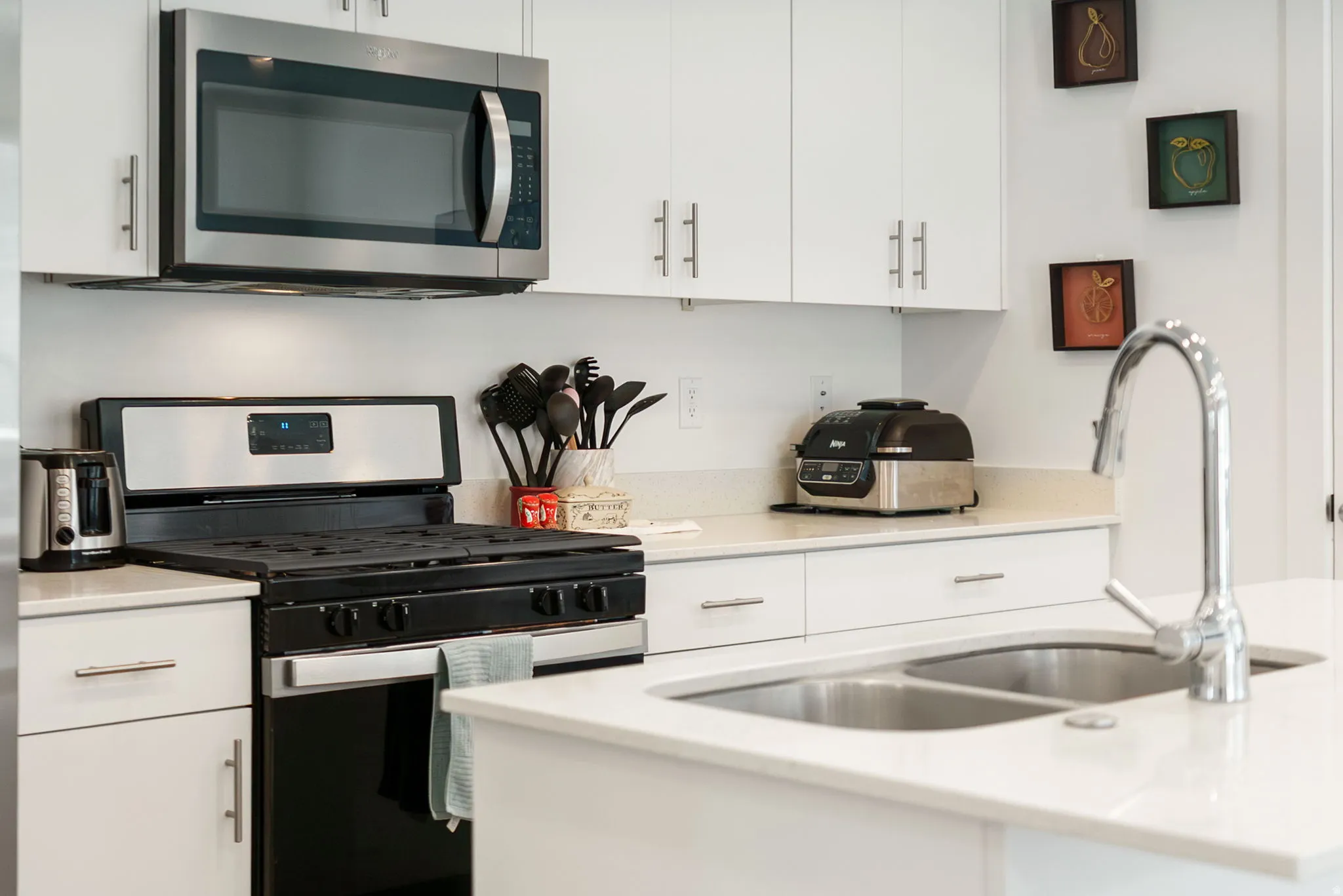 Kitchen featuring stainless steel appliances, white cabinets, and light stone countertops