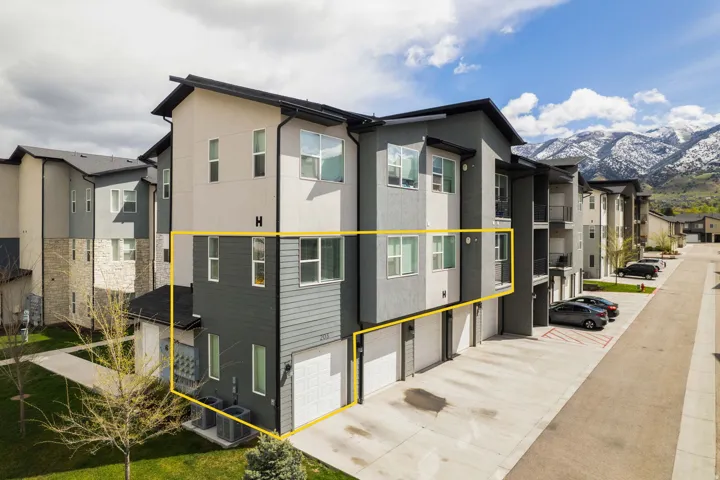 View of side of property featuring a garage, driveway, a mountain view, stucco siding, and a residential view