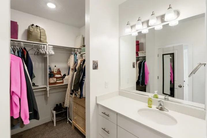 Full bath with a walk in closet, vanity, dark colored carpet, and a textured ceiling
