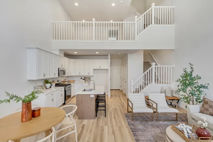 Two tone kitchen with stainless steel appliances, an island with sink, recessed lighting, light wood-style floors, and dual tone cabinets