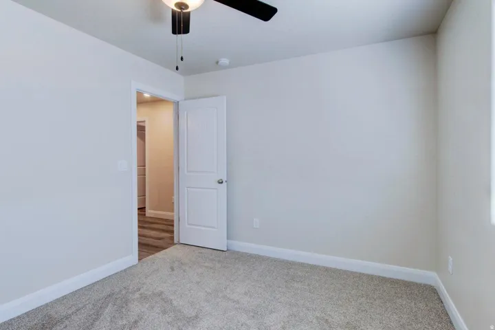 Empty room with light colored carpet and ceiling fan