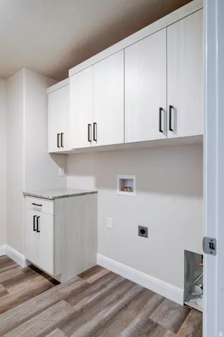 Laundry area with washer hookup, cabinet space, light wood-style floors, and hookup for an electric dryer