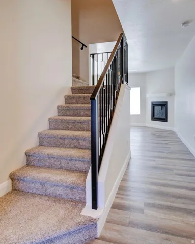 Stairway featuring a glass covered fireplace and wood finished floors