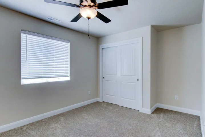 Unfurnished bedroom with light colored carpet, a closet, and ceiling fan