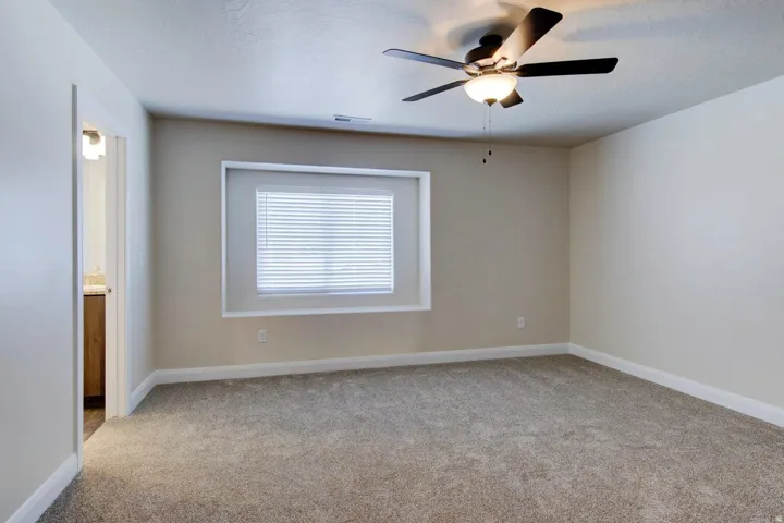 Spare room with light colored carpet, ceiling fan, and a textured ceiling