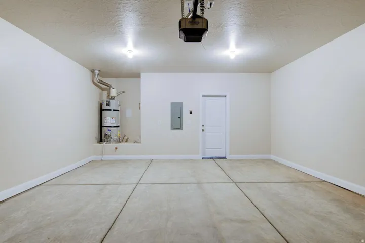 Garage with electric panel, strapped water heater, and a garage door opener