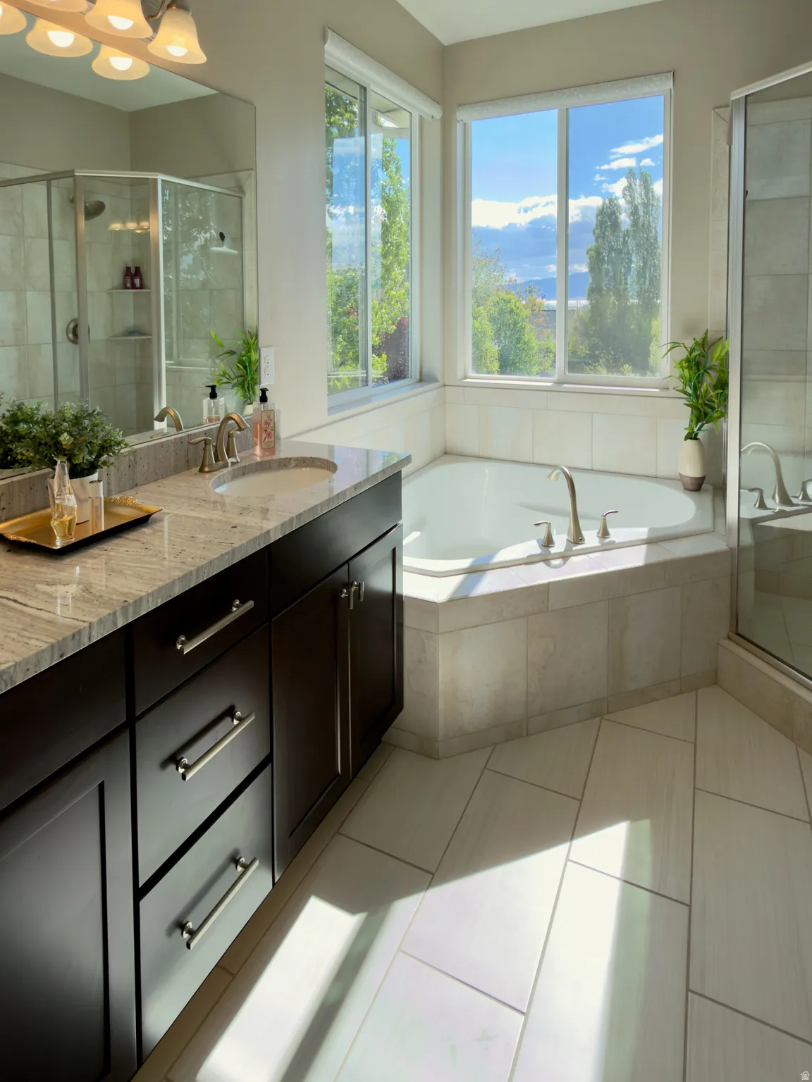 Bathroom featuring a stall shower, a mountain view, double vanity, a bath, and light tile patterned floors