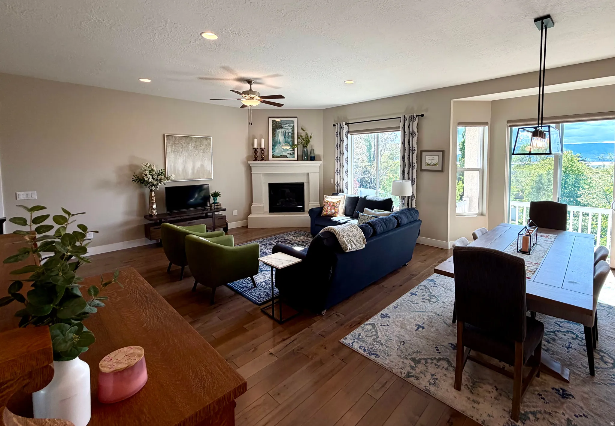 Living area with hardwood / wood-style flooring, ceiling fan, recessed lighting, a fireplace with raised hearth, and a textured ceiling