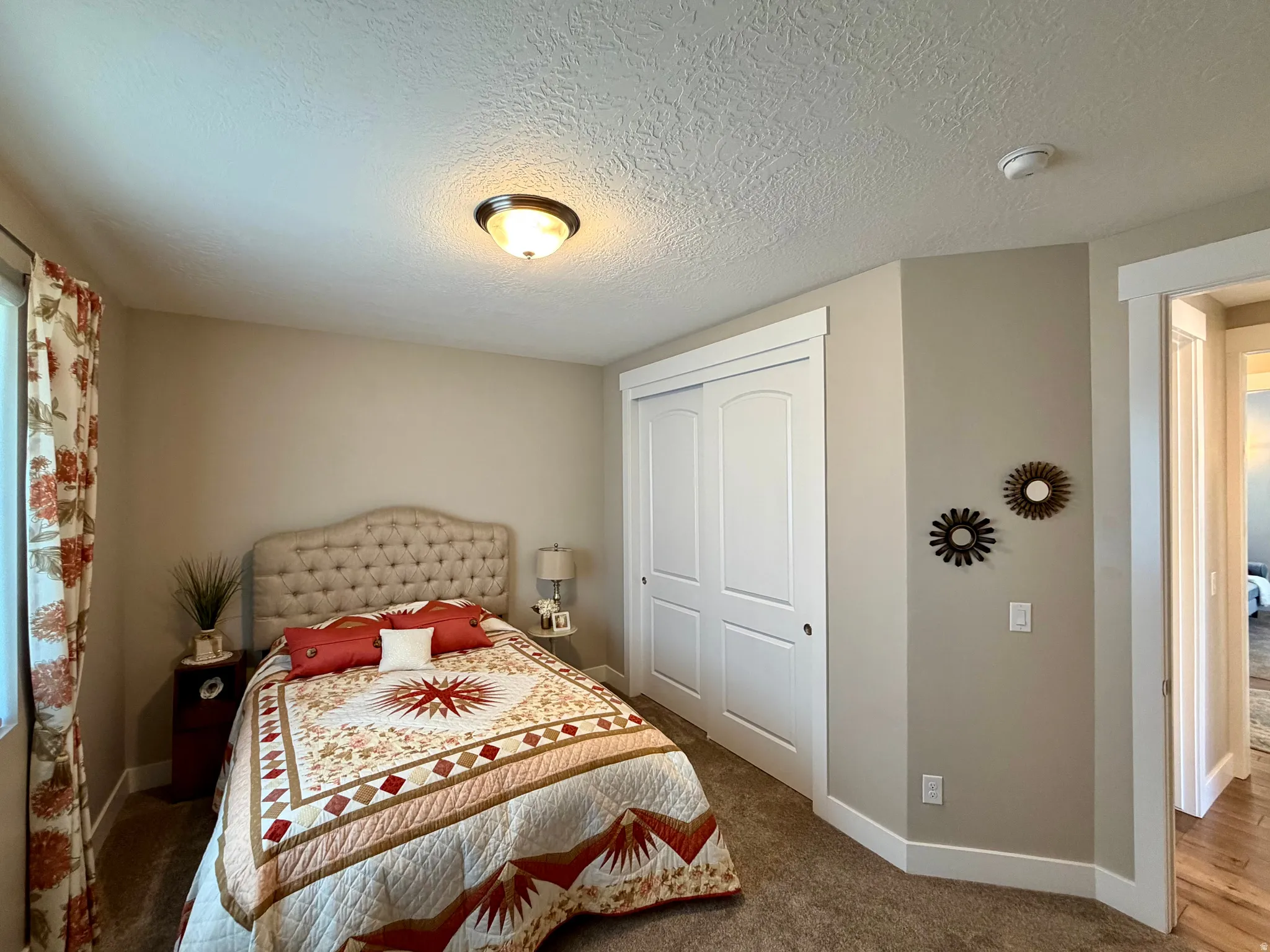 Bedroom with a closet, a textured ceiling, and dark carpet