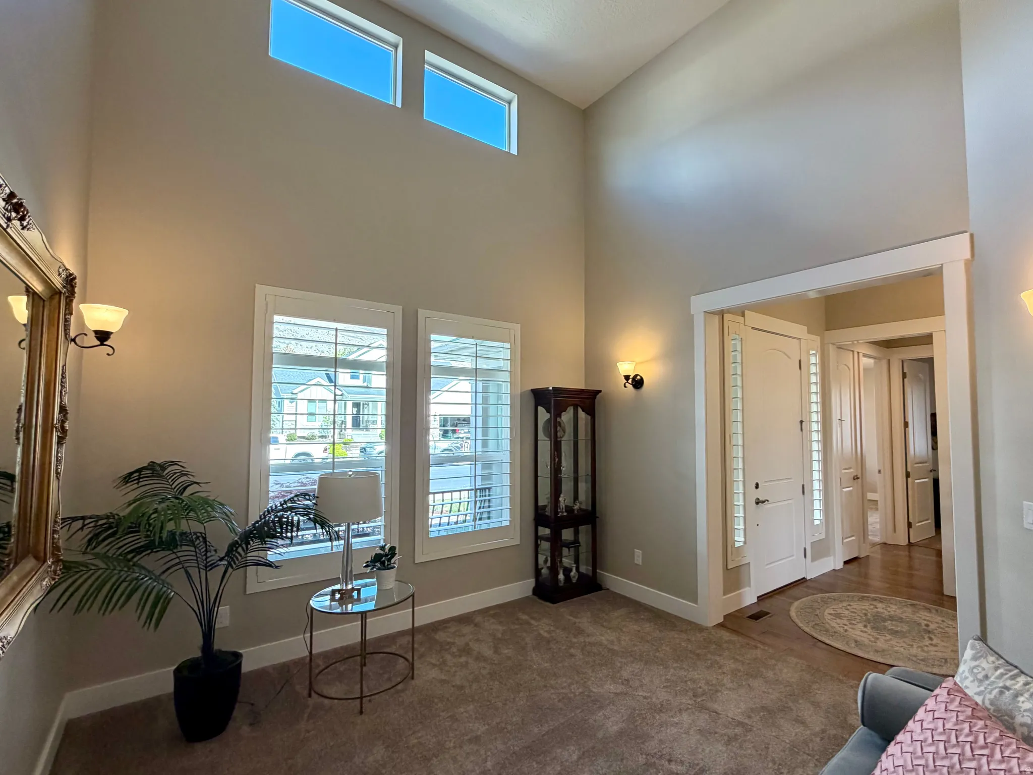 Sitting room with dark colored carpet and a high ceiling