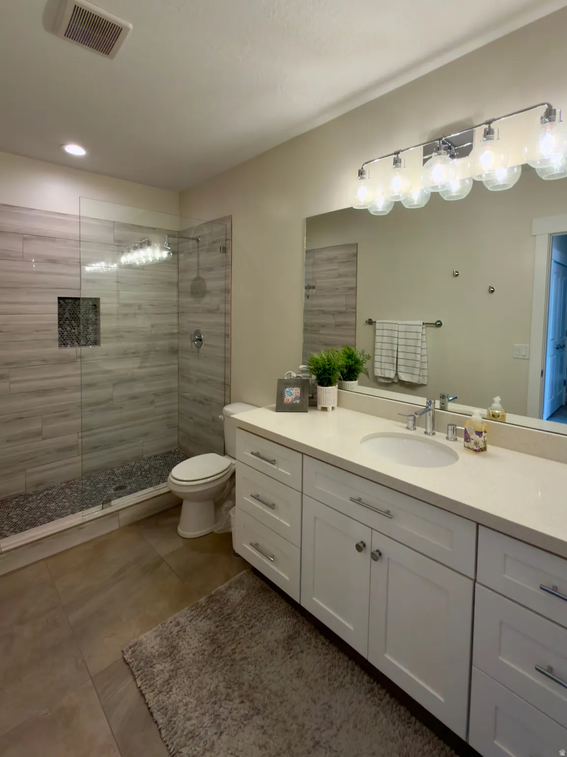 Full bath with vanity, walk in shower, dark tile patterned floors, and recessed lighting