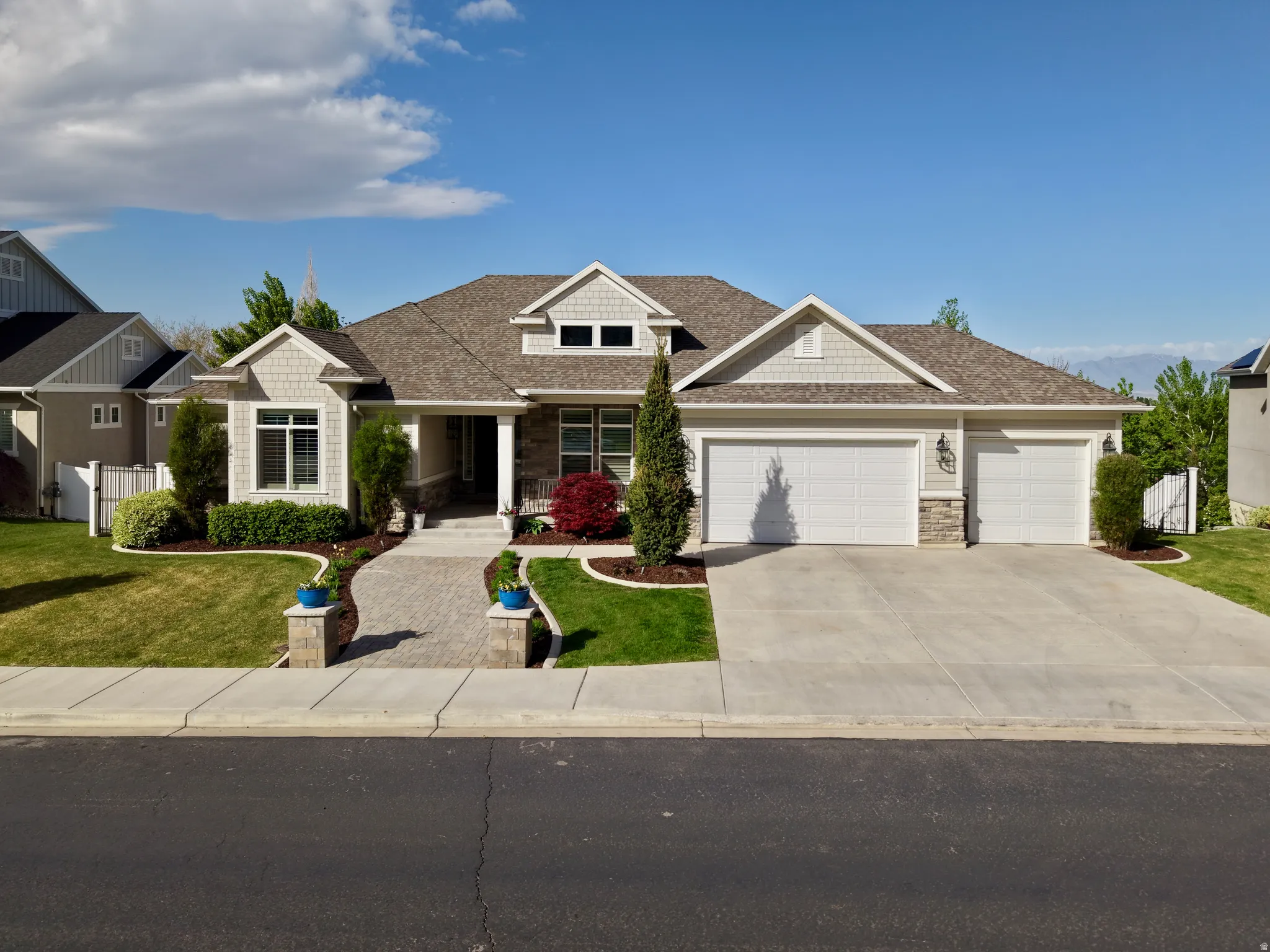 Craftsman-style house featuring stone siding, a shingled roof, a garage, driveway, and a porch