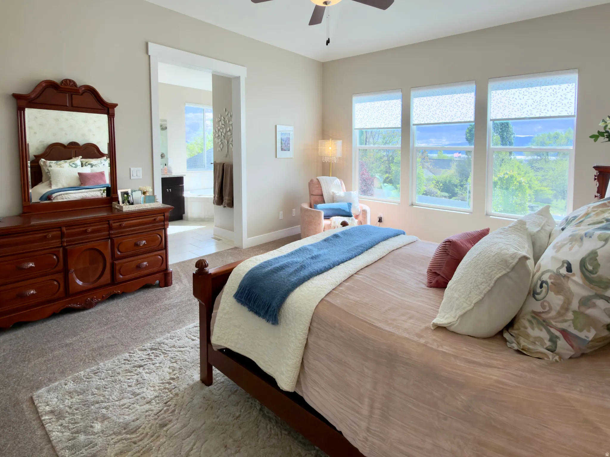 Bedroom with ensuite bathroom, light colored carpet, and ceiling fan