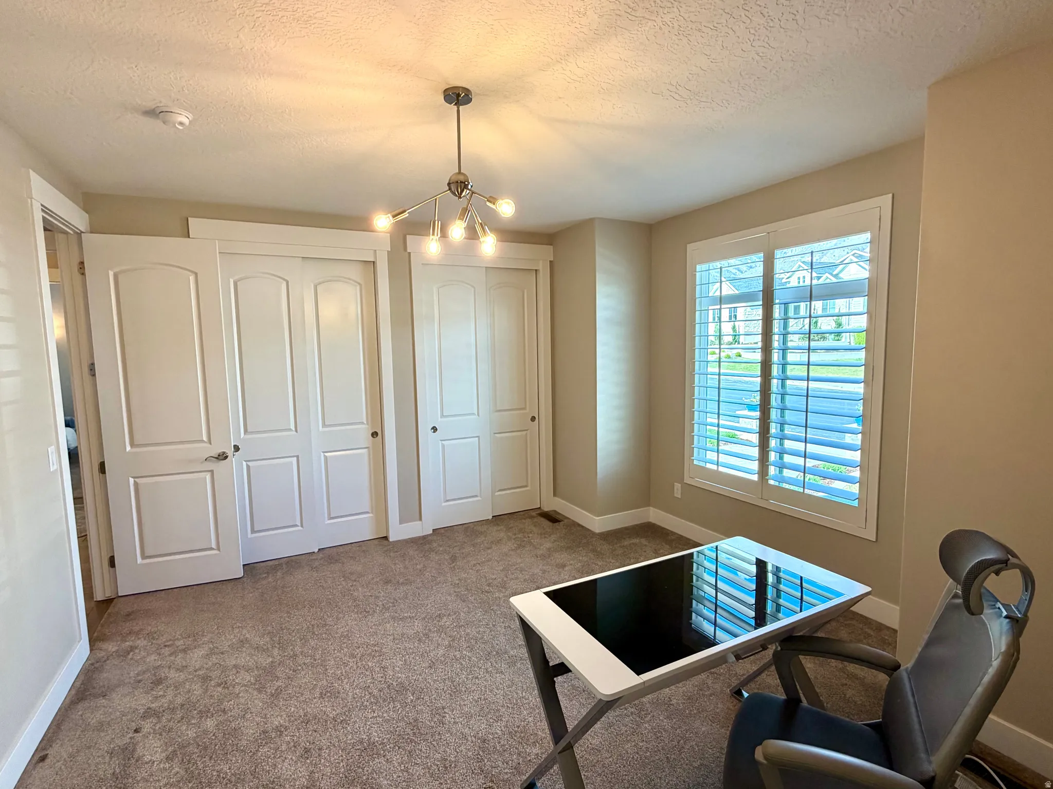 Carpeted home office featuring suspended lighting and a textured ceiling