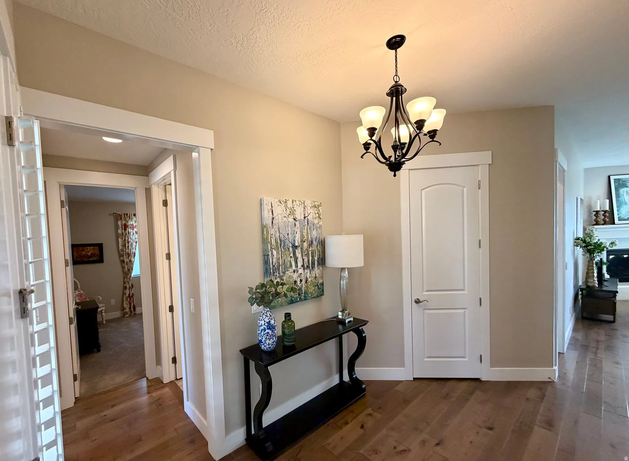 Hallway featuring dark wood-type flooring, suspended lighting, and a textured ceiling