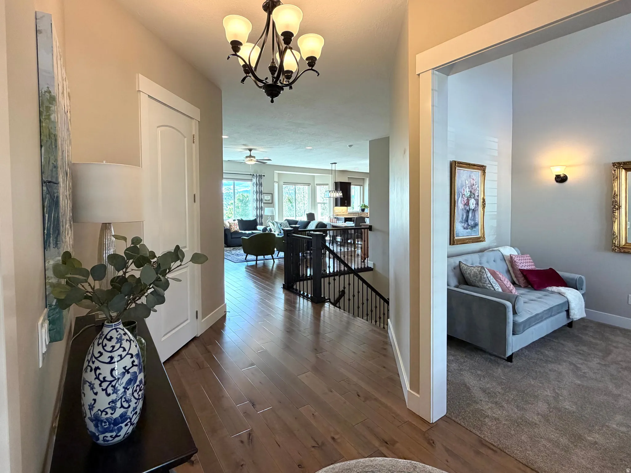 Hall with an upstairs landing, dark wood-type flooring, and hanging lights