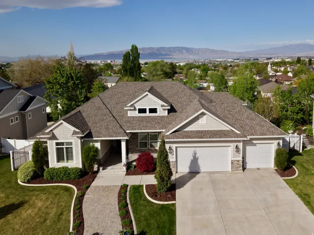 Craftsman-style home featuring stone siding, roof with shingles, an attached garage, and concrete driveway
