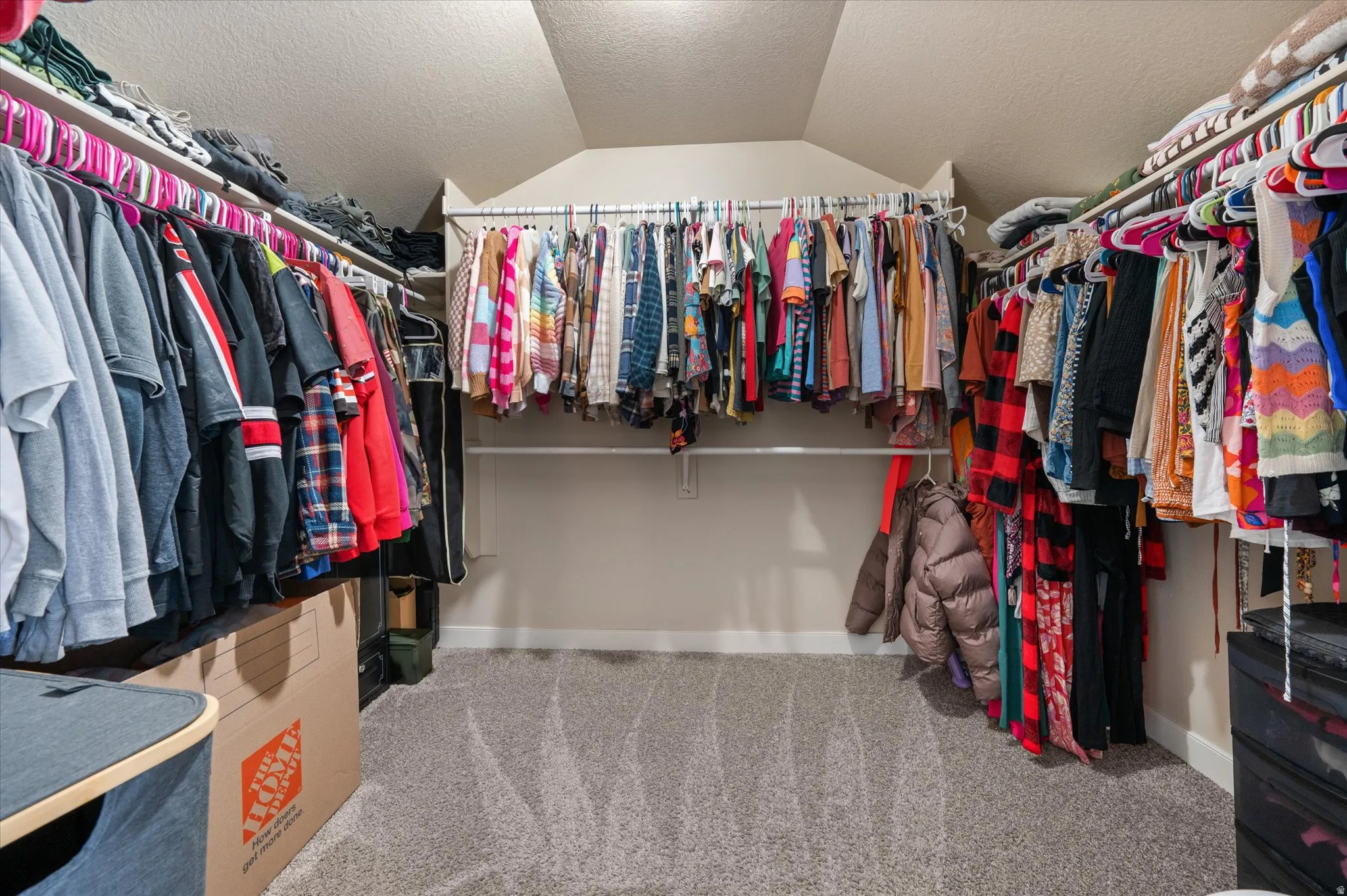 Walk in closet with light carpet and vaulted ceiling