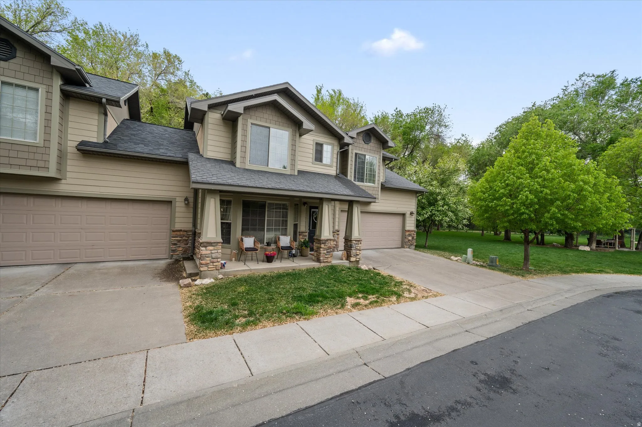 Craftsman house featuring stone siding, driveway, a porch, and a front yard