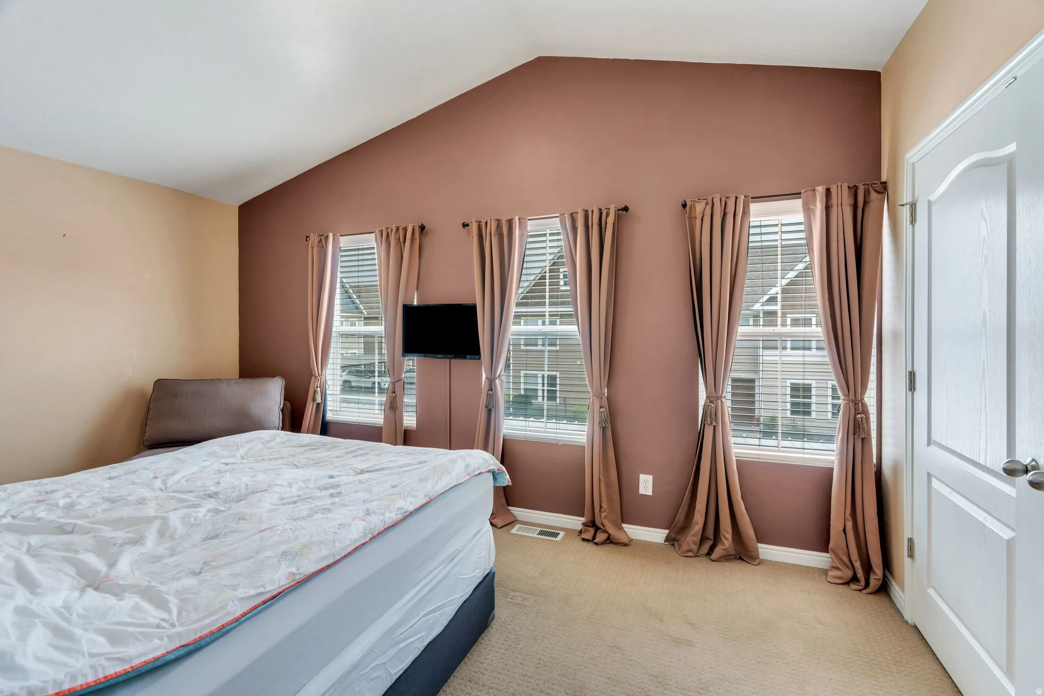 Bedroom featuring light carpet and multiple windows