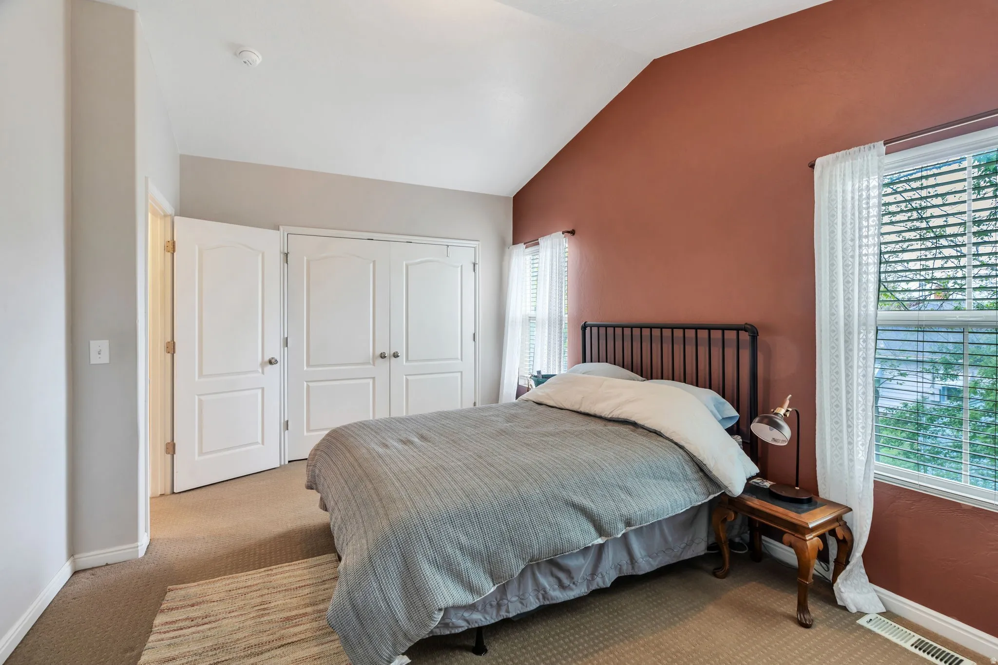 Bedroom with light colored carpet, lofted ceiling, and a closet