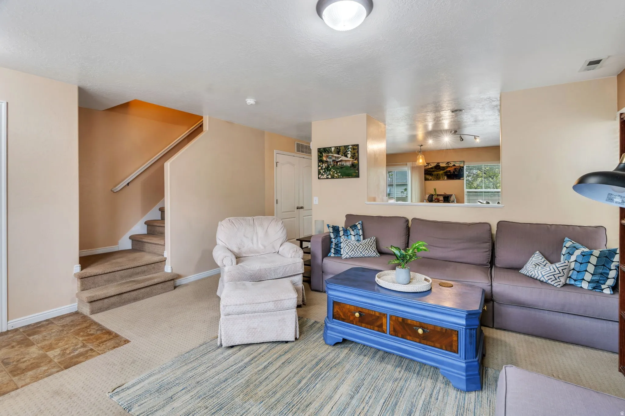 Living area featuring light carpet and stairs