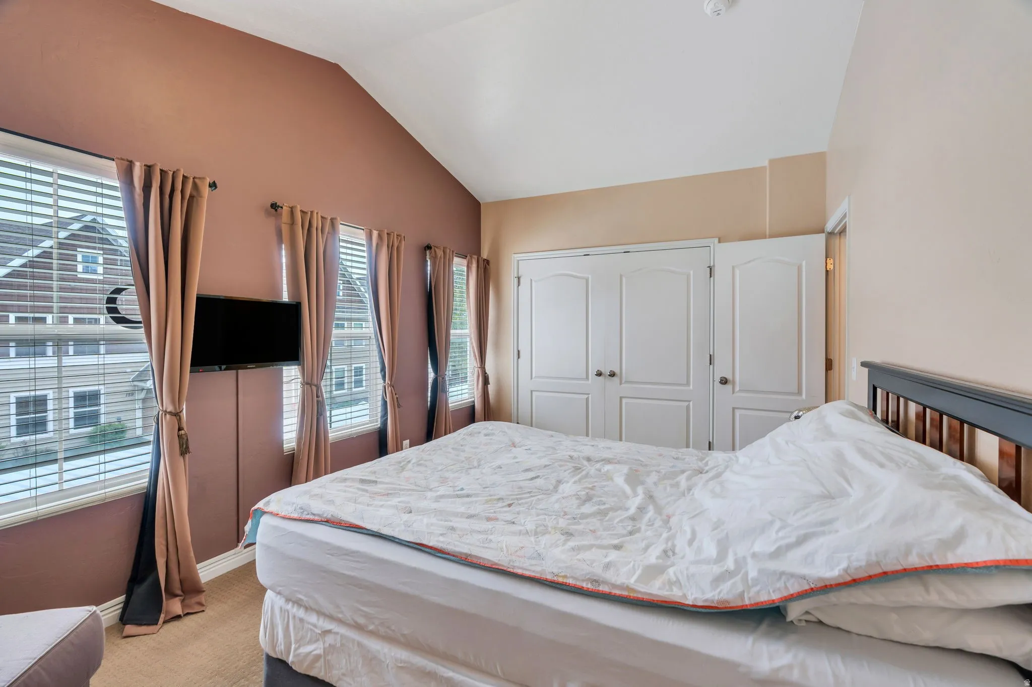 Bedroom with vaulted ceiling, a closet, and light colored carpet