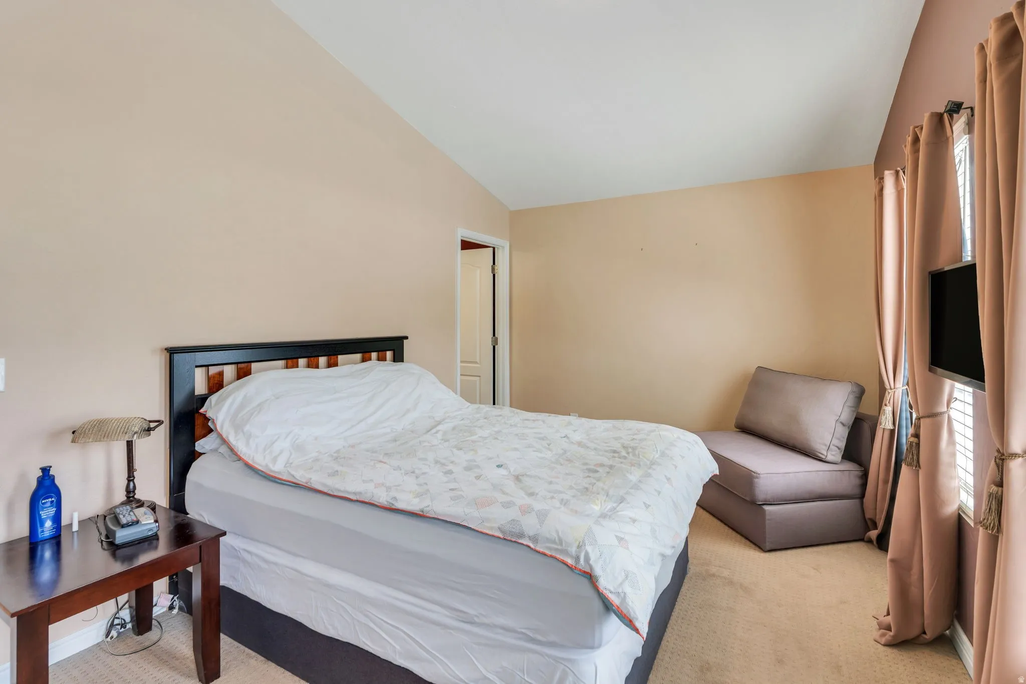 Bedroom with light colored carpet and lofted ceiling