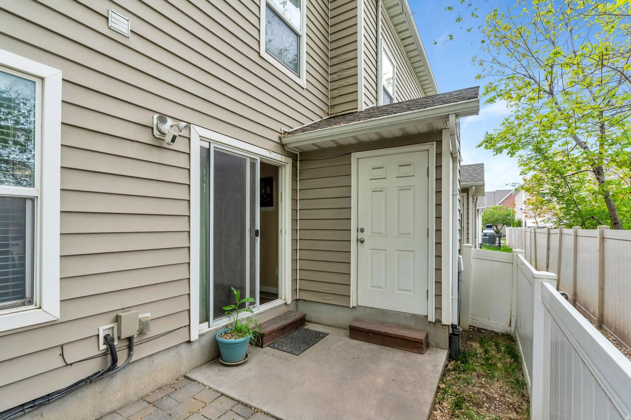 Property entrance featuring roof with shingles and a patio