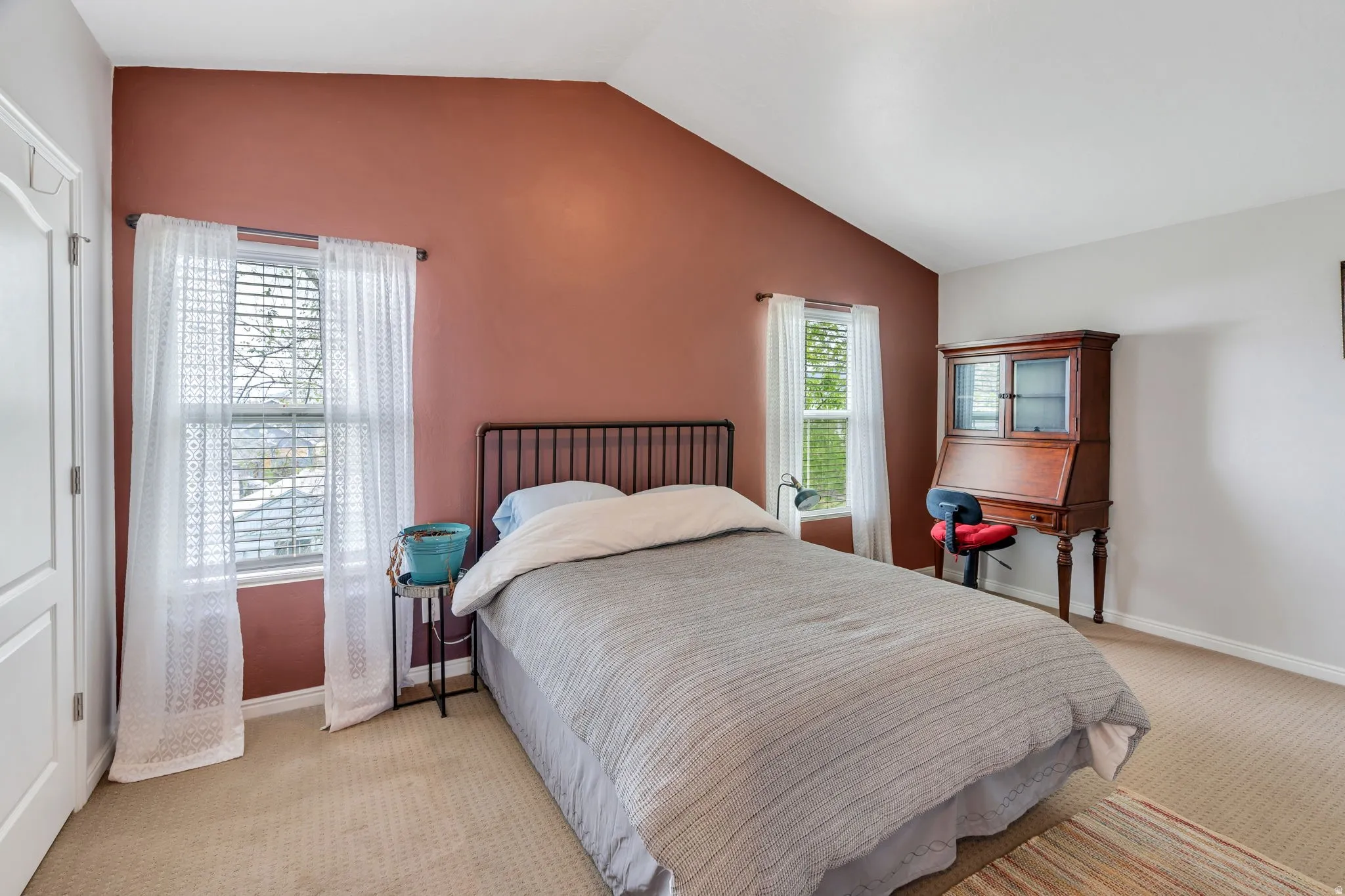 Bedroom with light colored carpet, vaulted ceiling, and a closet