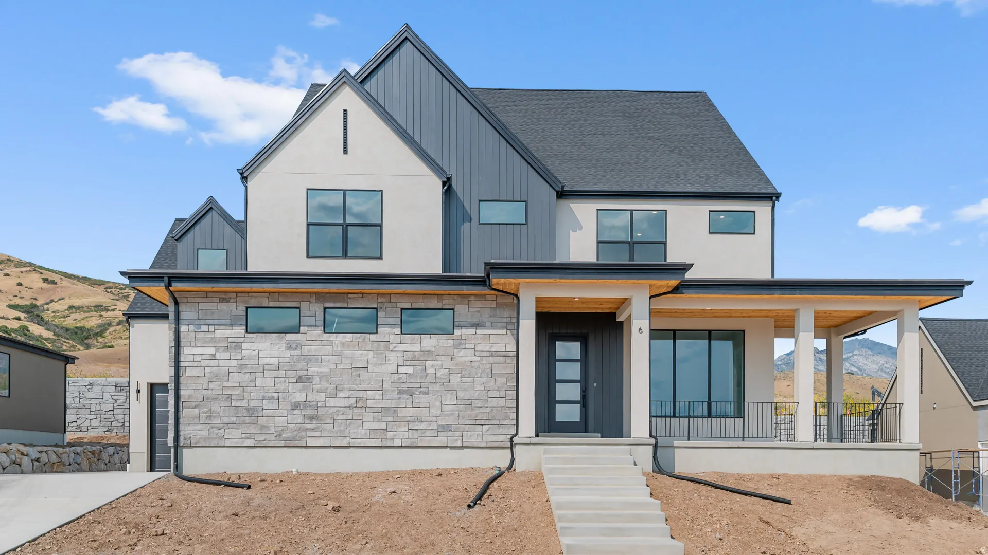 View of front of home with stone siding, a mountain view, a porch, and a shingled roof